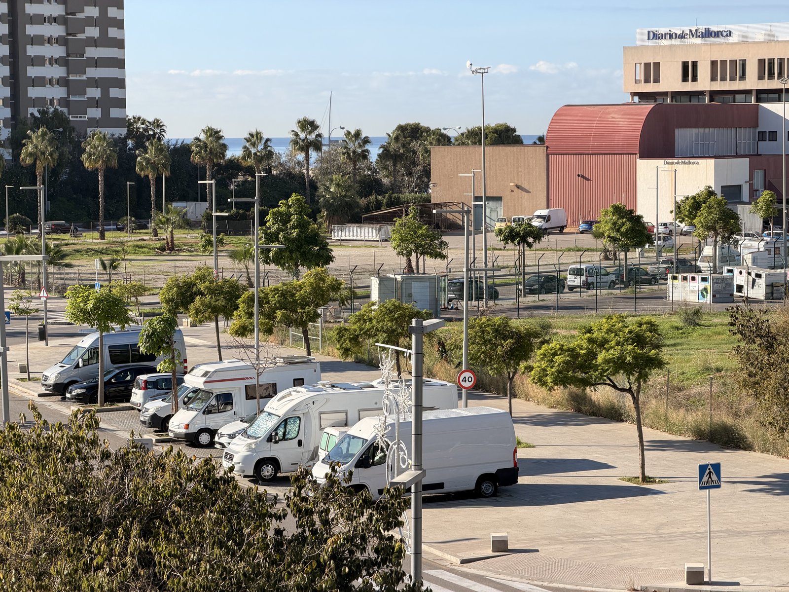 Mehrere geparkte Wohnmobile und Vans in Nou Llevant, im Hintergrund das Gebäude des Diario de Mallorca und das Meer