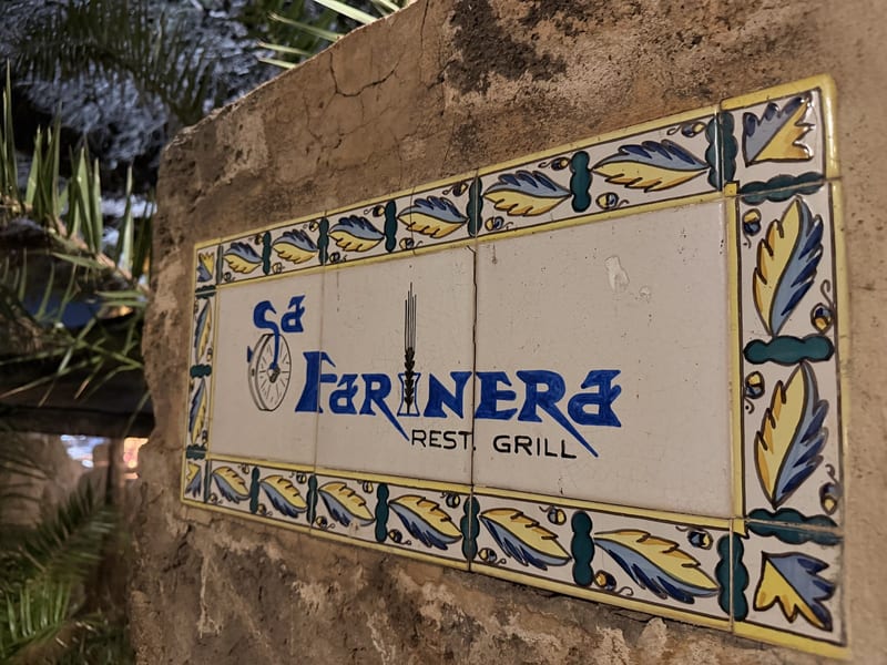 Keramikschild „Sa Farinera Rest. Grill“ am Abend am Eingang des Restaurants