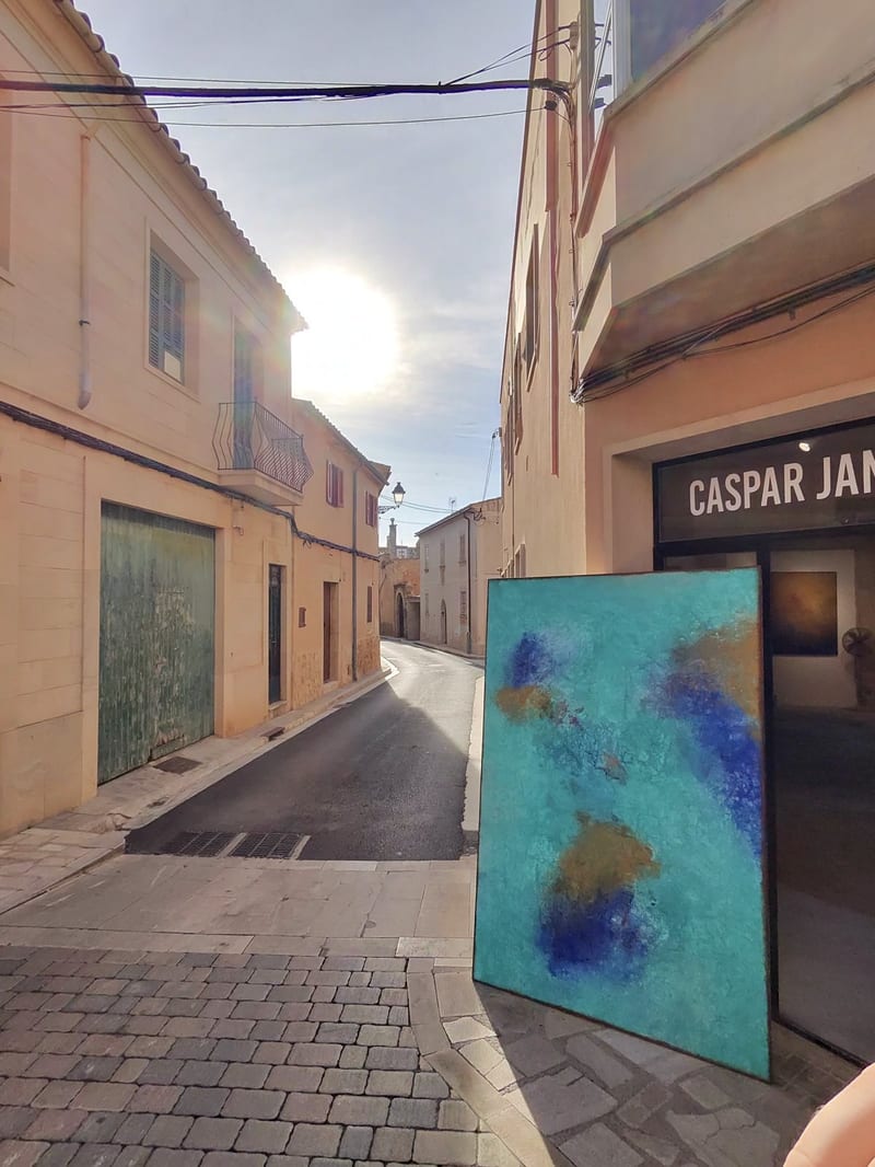 Gasse in Santanyí mit Galerie-Eingang und einem großen blauen abstrakten Gemälde an der Hauswand